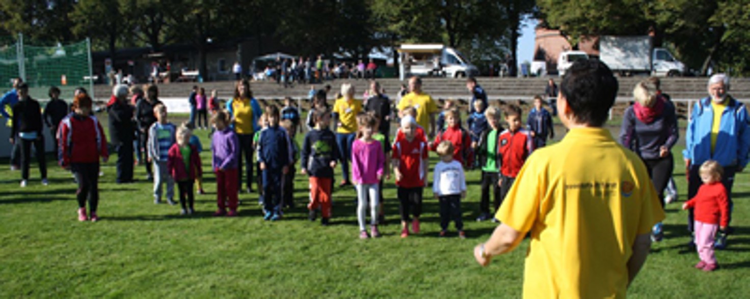 Eine größere Menge Kinder steht vor einem Mann, der ihnen etwas erklärt