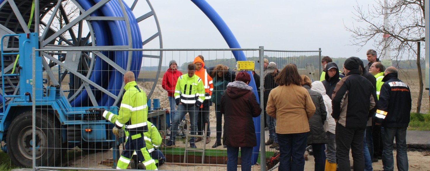 Mehrere Menschen, manche in Arbeitskleidung, stehen an einer Baustelle