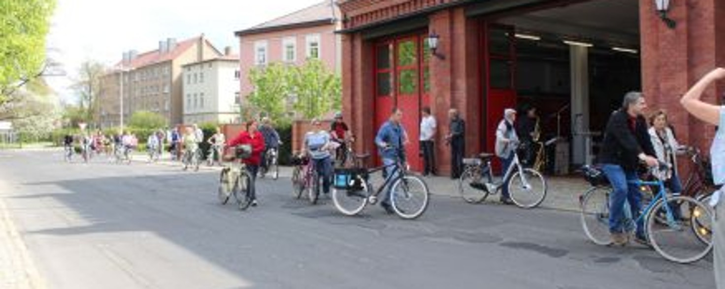 Eine Gruppe Radfahrer steht mit ihren Rädern vor einem Backstein-Gebäude