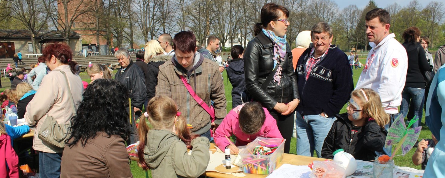 Mehrere Menschen stehen neben einem Tisch, auf dem Kinder gerade malen