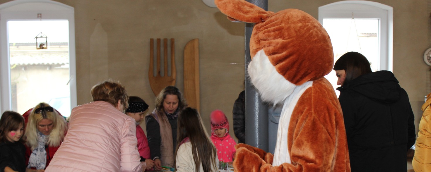 Frauen und Kinder stehen an einem Tisch und backen Plätzchen, ein Mensch im Hasenkostüm steht daneben