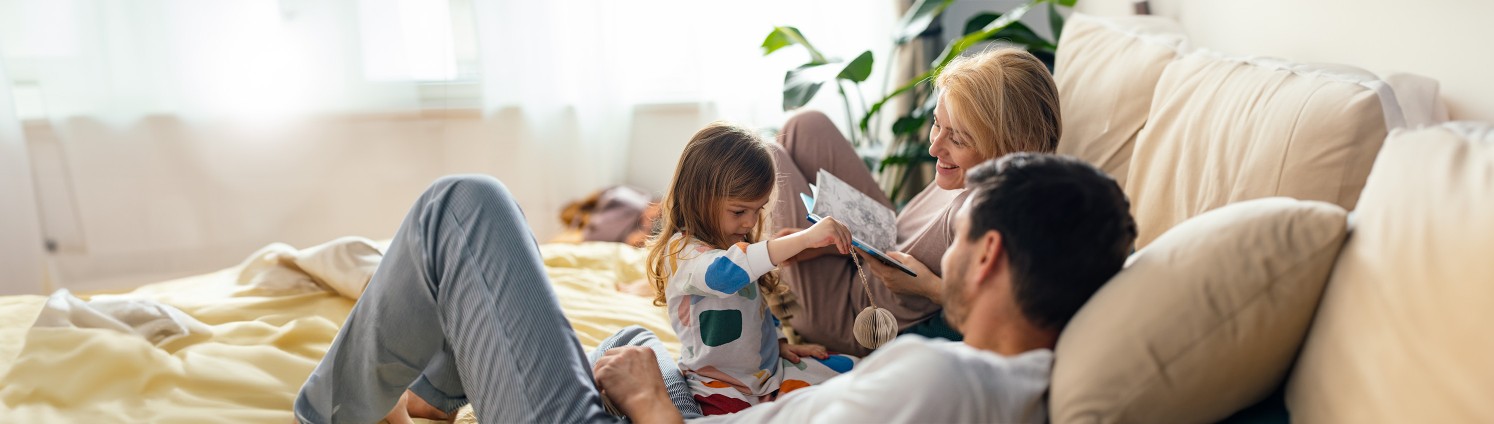 Lächelndes Paar mit Kind spielt auf der Couch