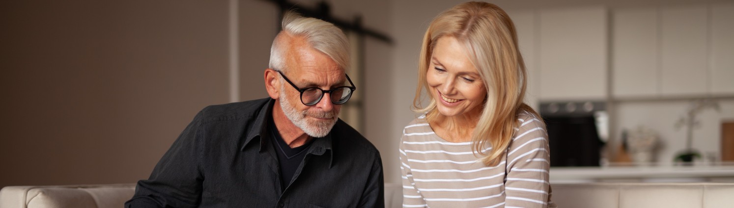 Mann und Frau sitzen auf dem Sofa und schauen auf Dokumente