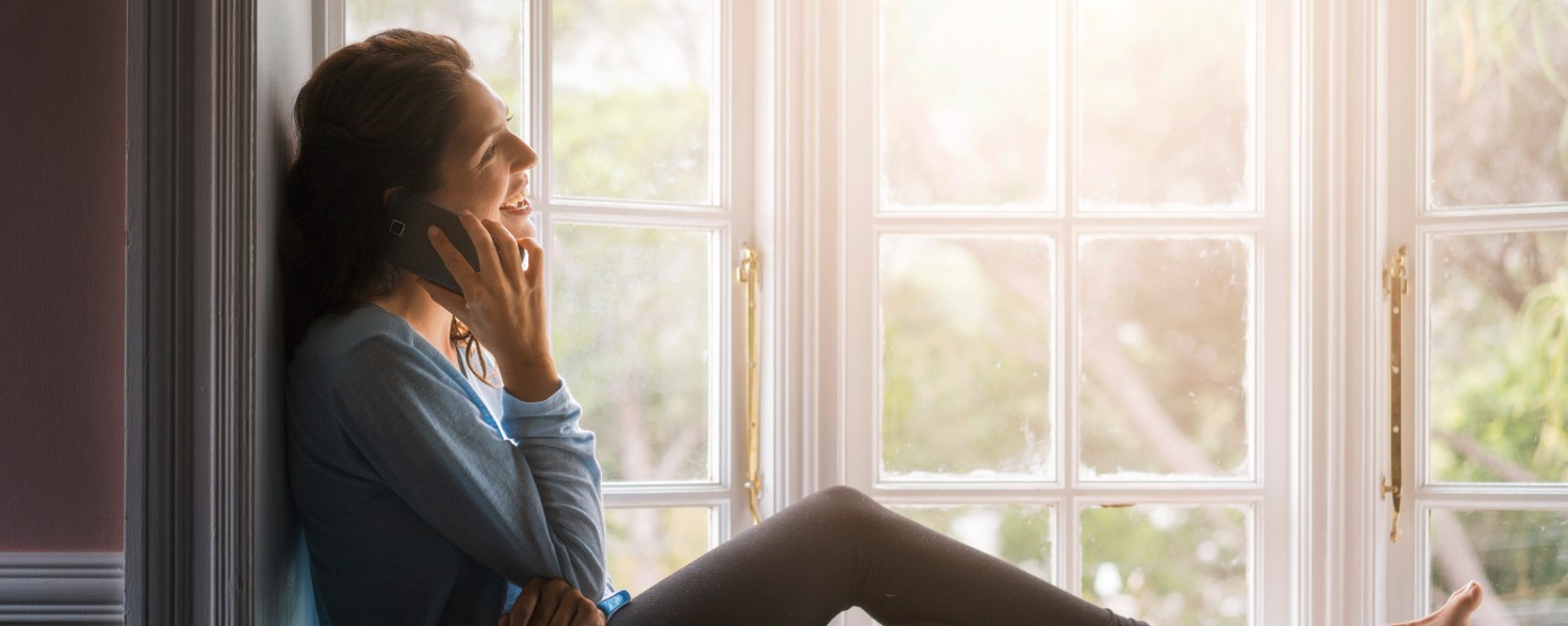 Eine Frau telefoniert am Fenster